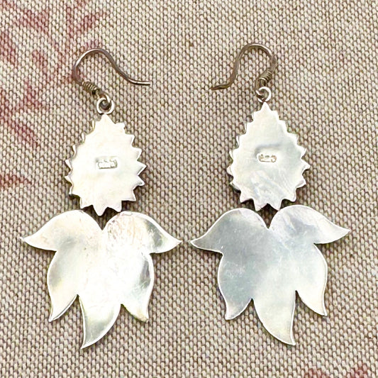 Pair of silver floral earrings on a textured fabric background