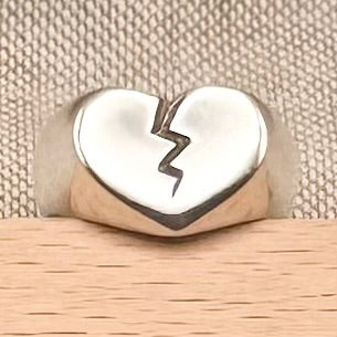 Silver heart-shaped ring with a crack design on a beige background