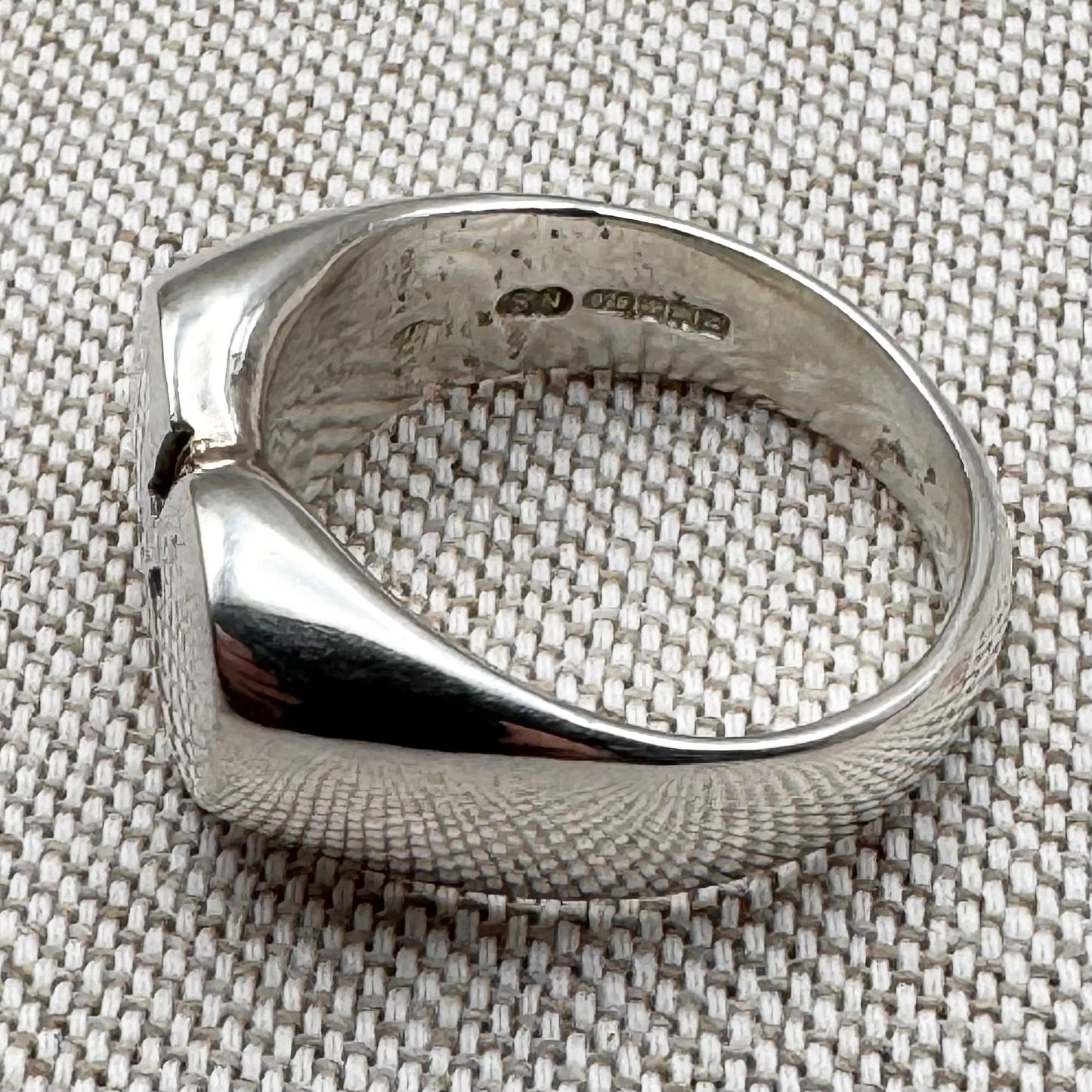Silver ring with a textured surface on a textured fabric background