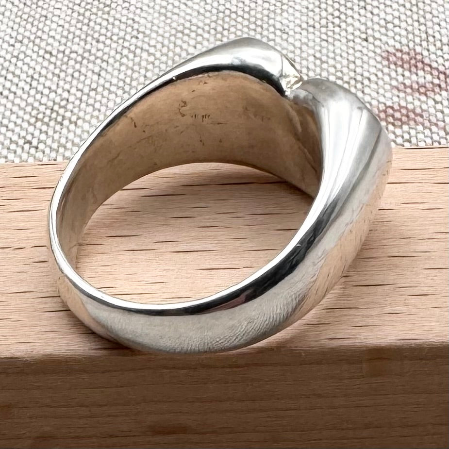 Silver ring on a wooden surface with a textured fabric background