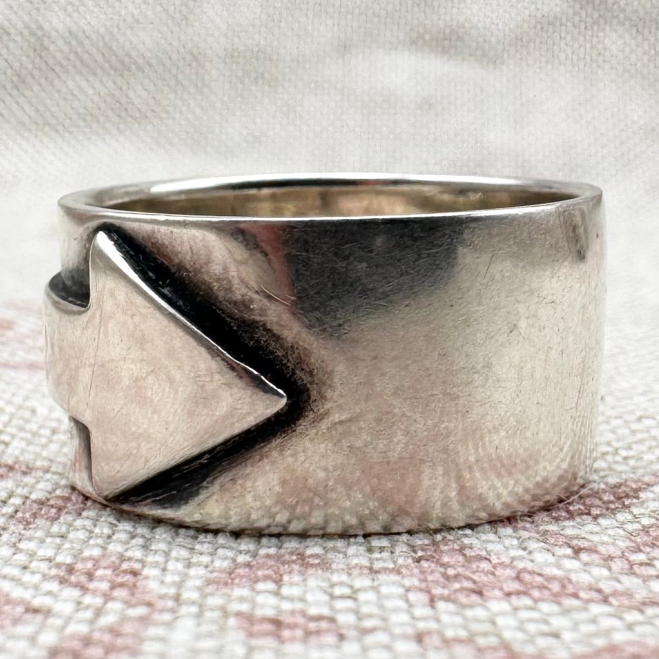 Silver ring with a geometric design on a textured fabric background