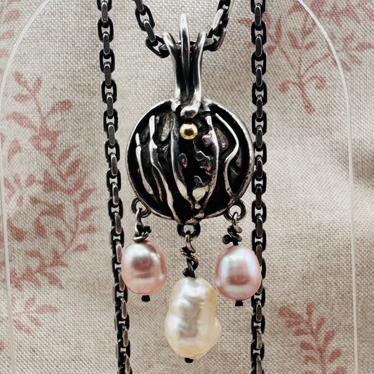 Silver pendant necklace with three pearls on a floral background