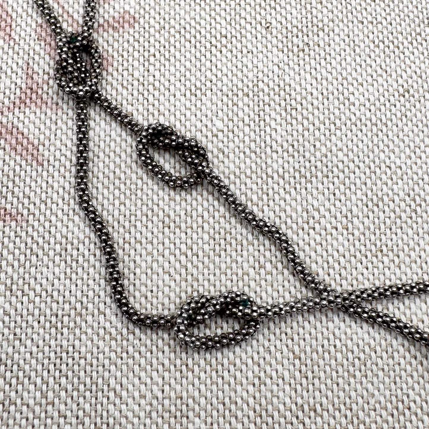 Close-up of a beaded necklace on a textured fabric background