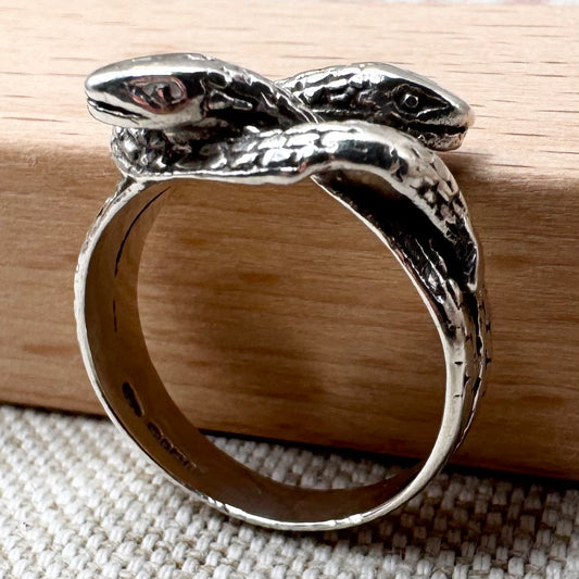 Silver snake-shaped ring on a wooden surface