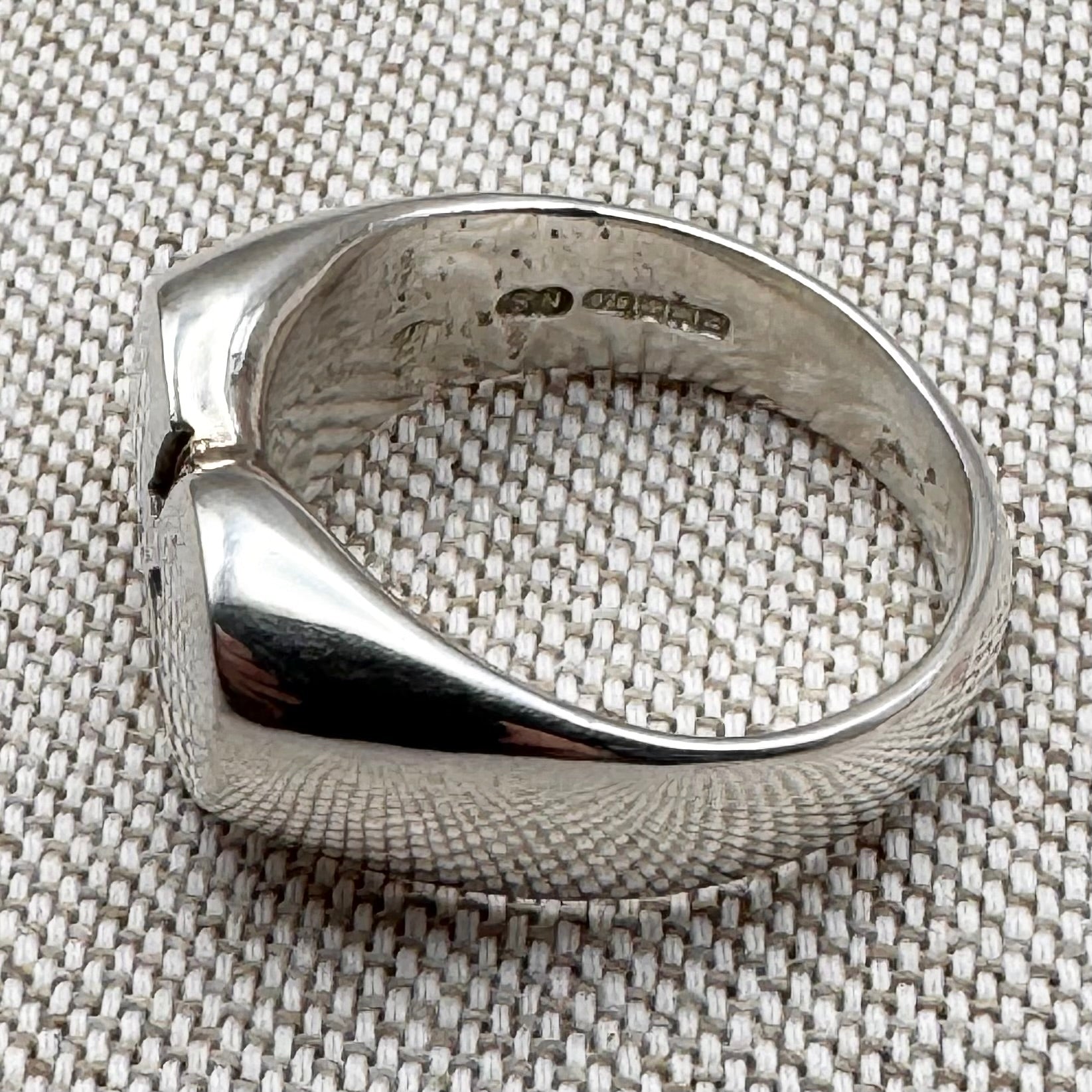 Silver ring with a textured surface on a textured fabric background
