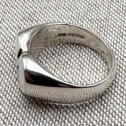 Silver ring with a textured surface on a textured fabric background