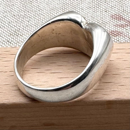 Silver ring on a wooden surface with a textured fabric background