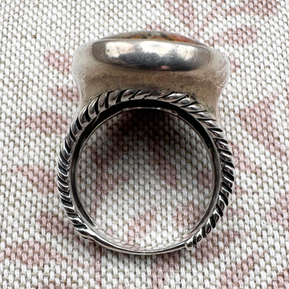 Silver ring with textured band on a textured fabric background