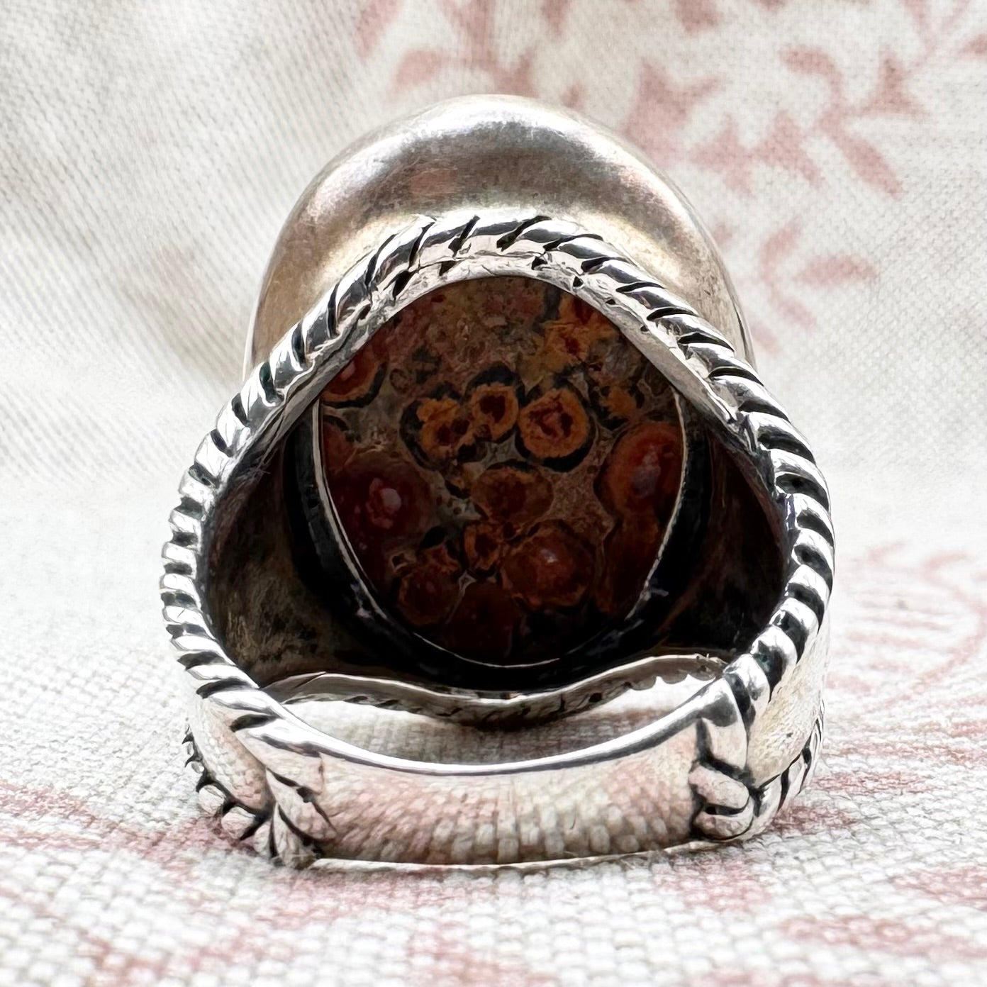 Silver ring with a textured band on a textured white background
