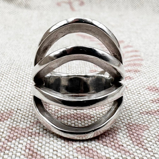 Silver ring with a wavy design on a cloth surface