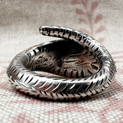Silver snake-shaped ring on a textured fabric background