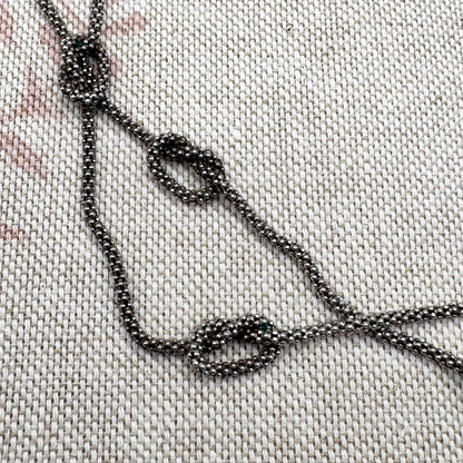 Close-up of a beaded necklace on a textured fabric background