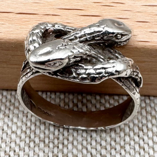 Silver snake-shaped ring on a textured surface