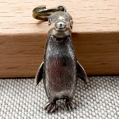 Silver penguin keychain on a wooden surface
