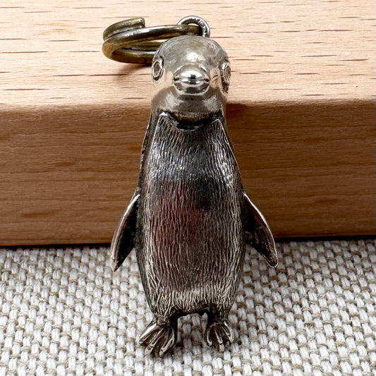 Silver penguin keychain on a wooden surface
