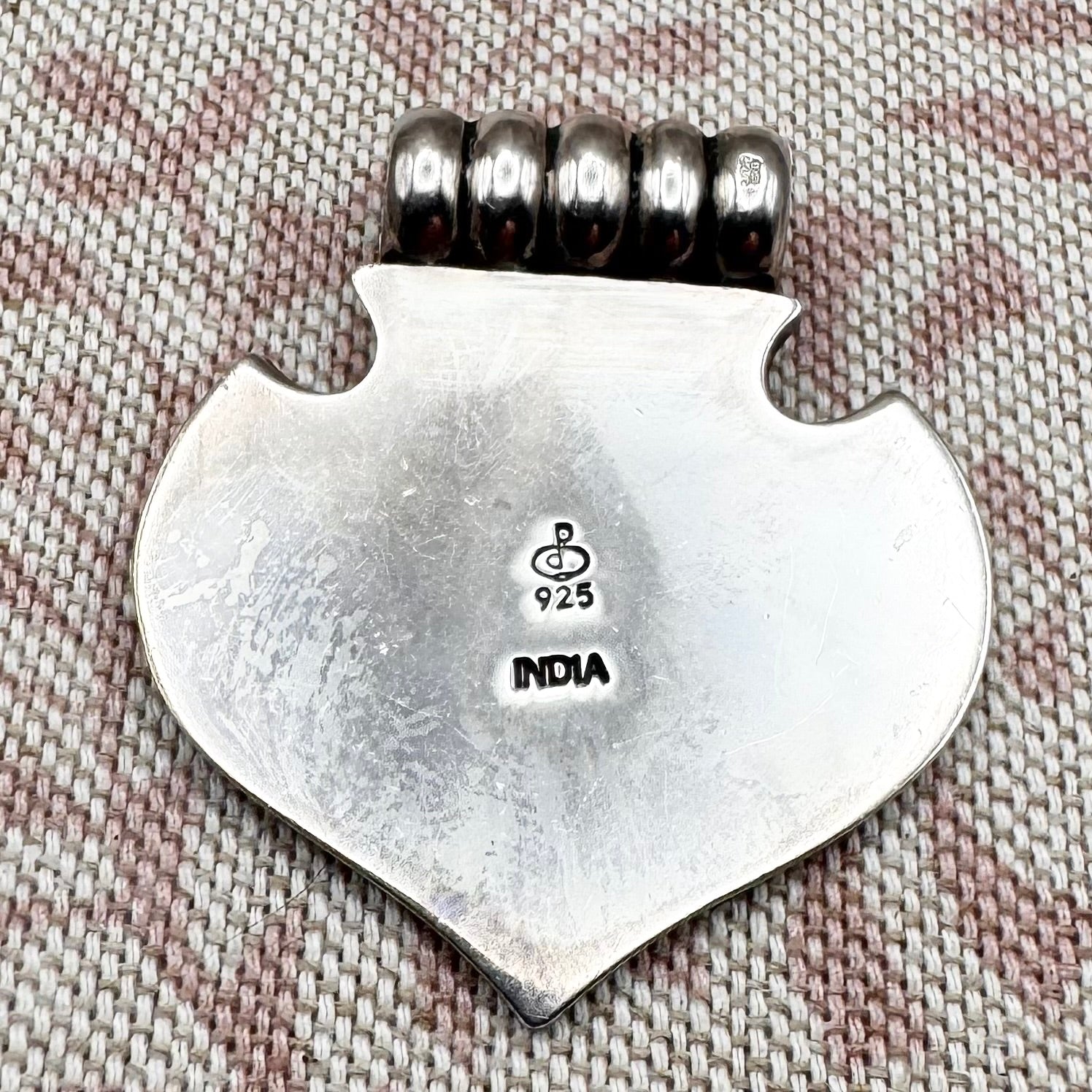 Silver axe-shaped pendant with beads on a textured fabric background