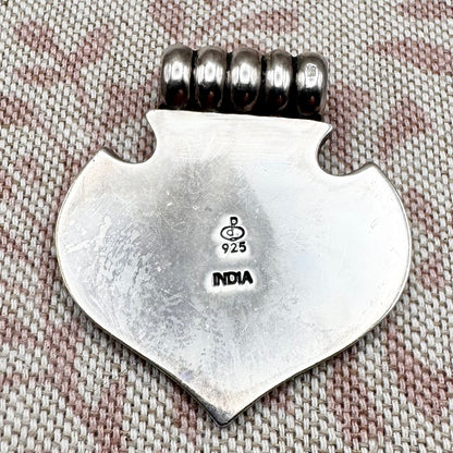 Silver axe-shaped pendant with beads on a textured fabric background