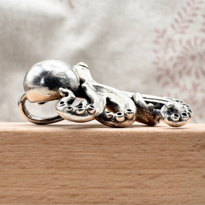 Silver octopus-shaped ring on a wooden surface with a blurred background