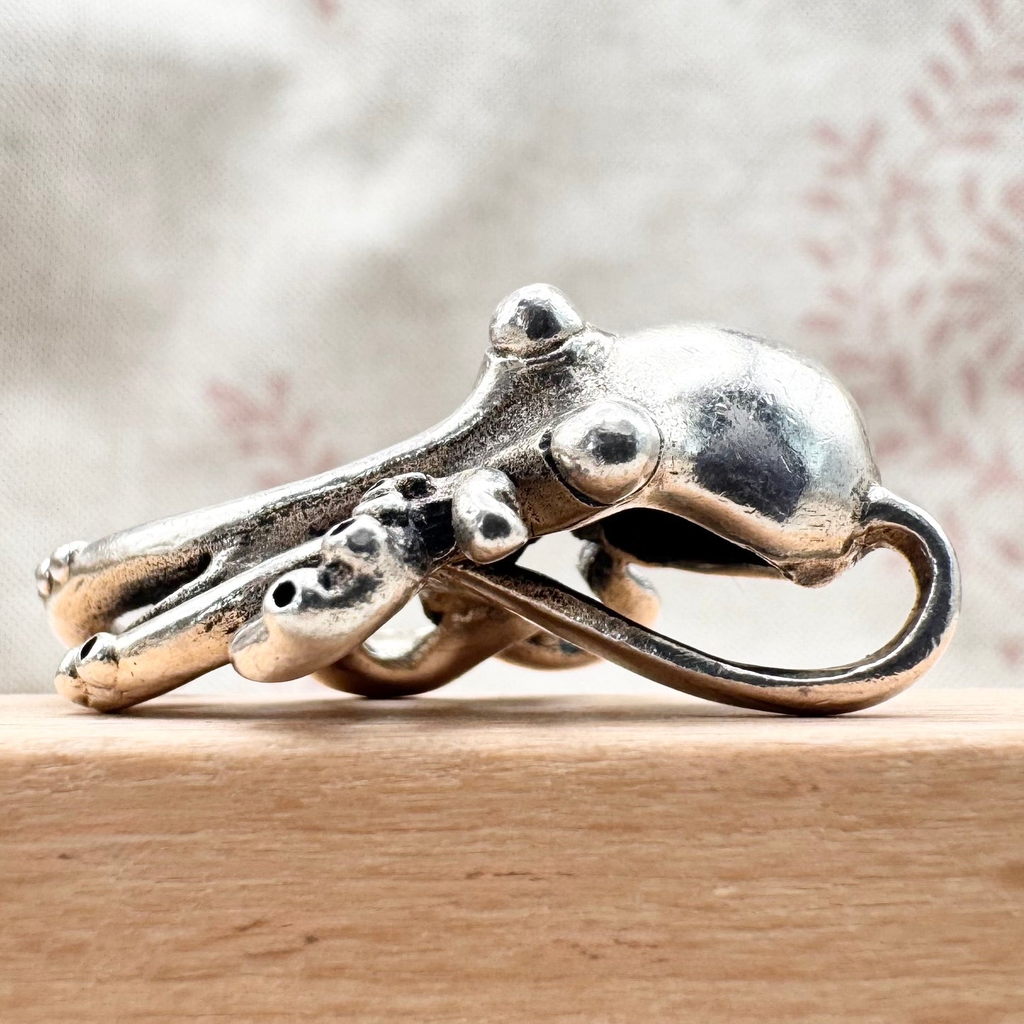 Silver octopus-shaped ring on a wooden surface with a blurred background