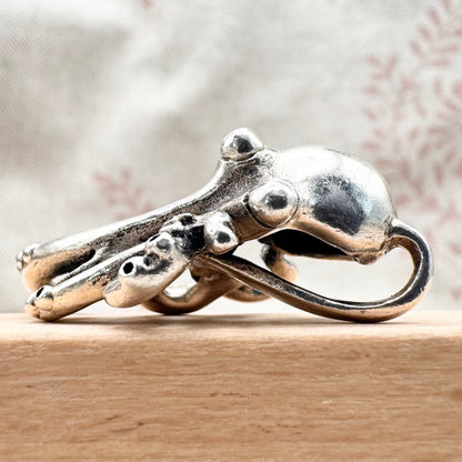 Silver octopus-shaped ring on a wooden surface with a blurred background