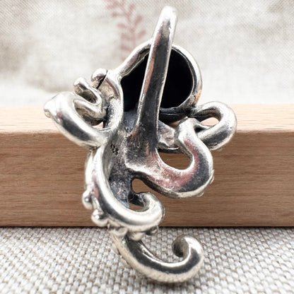 Silver pendant with intricate design on a wooden stick