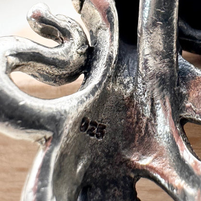 Close-up of a silver pendant with intricate design on a wooden surface