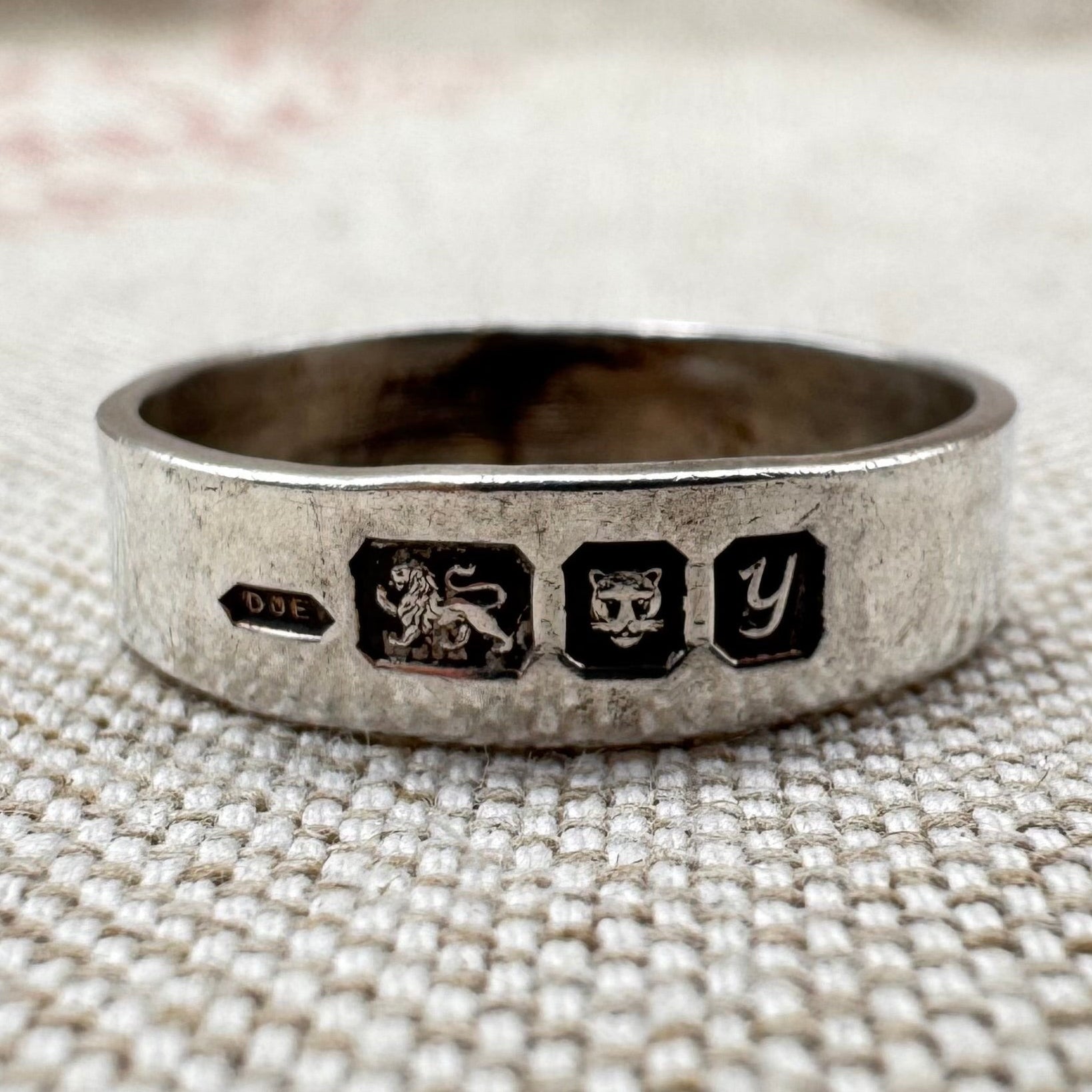 Silver ring with hallmarks on the outside of the band.