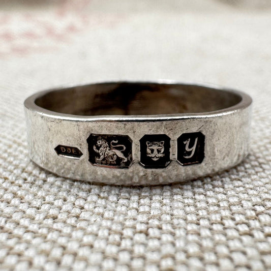 Silver ring with hallmarks on the outside of the band.