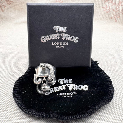 Silver skull and snake ring on a black cushion with 'The Great Frog London' branding.