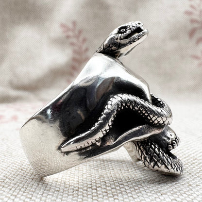 Silver snake-shaped ring on a textured surface