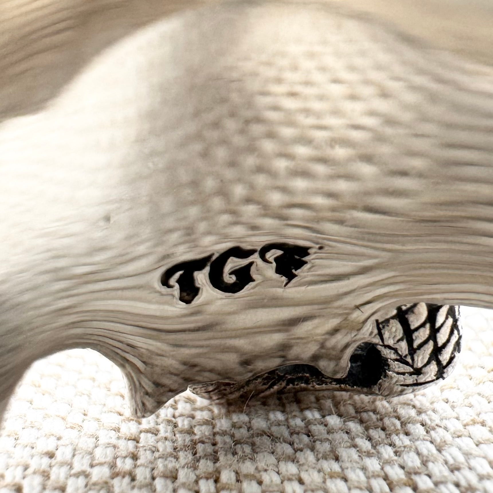 Wooden object with 'TGF' branding on a textured surface