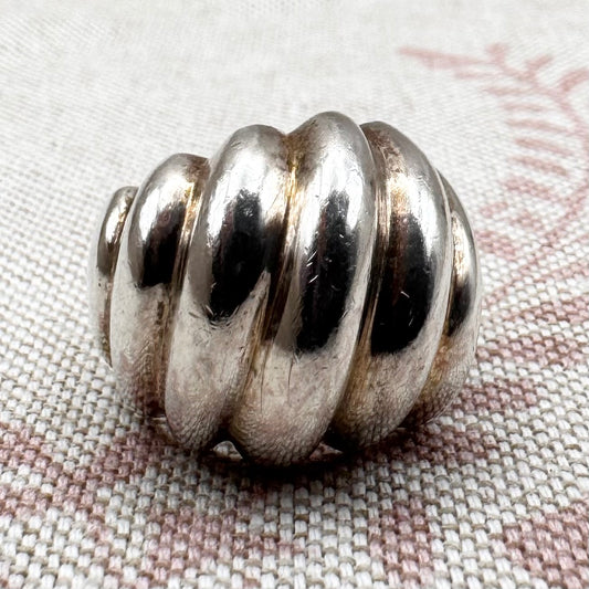 Silver spiral bead on a textured fabric background