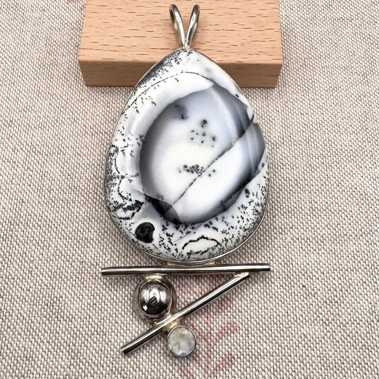 Marble-patterned pendant with a wooden block on a textured beige surface