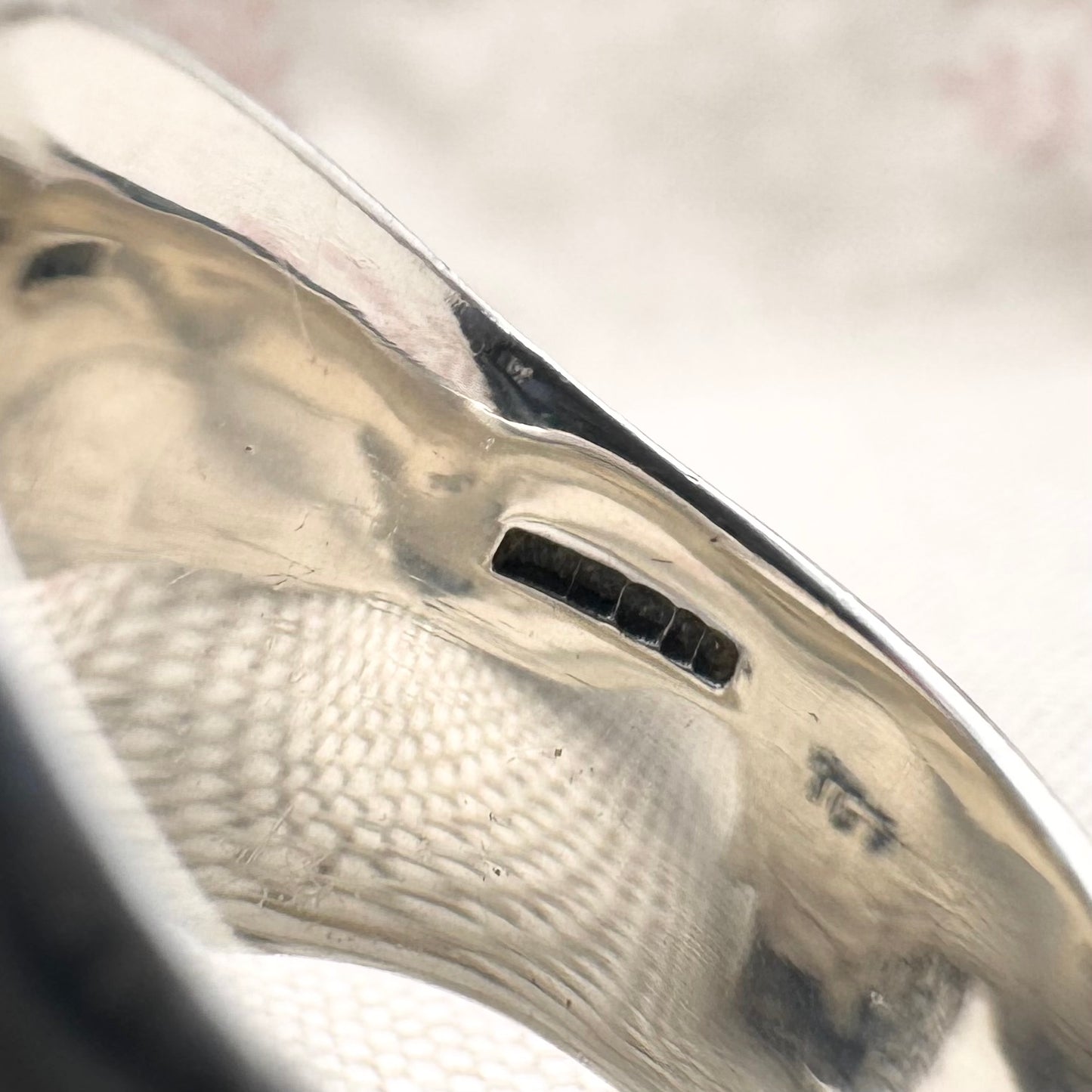 Close-up of a silver ring with hallmarks  on a white background
