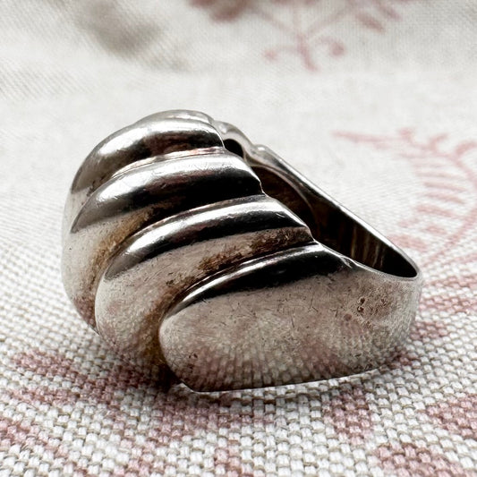 Silver ring with a textured design on a fabric background